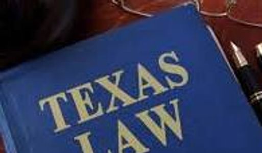 A Texas Law book with glasses and a pen nearby.