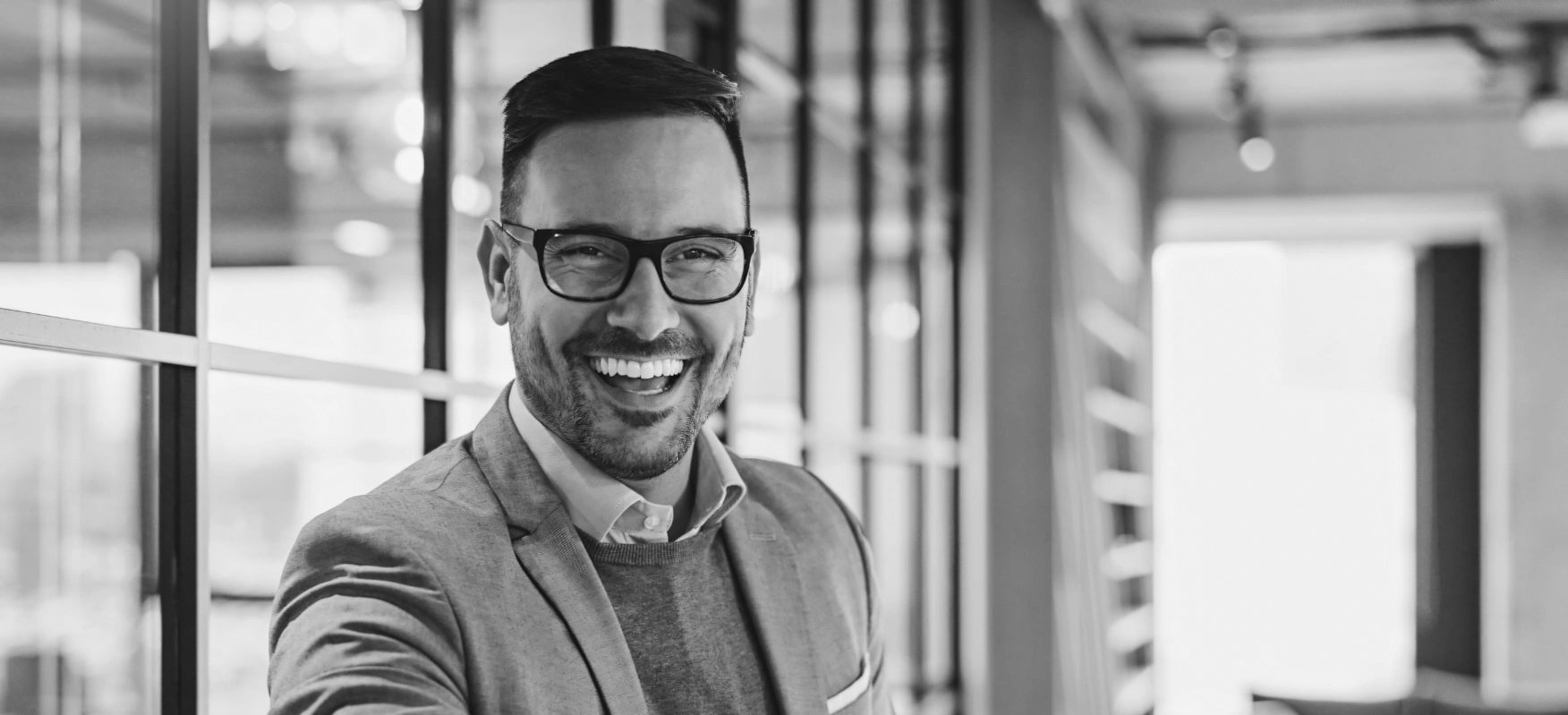 Black and white photo of a male with dark hair and glasses smiling.