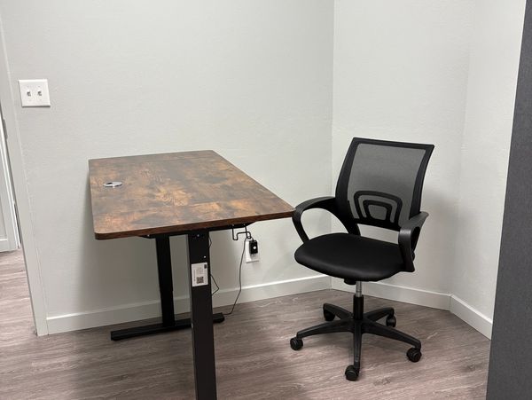 Minimalist office corner with a wooden desk and ergonomic black chair.