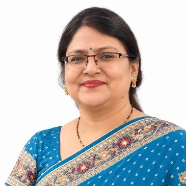Smiling woman in blue saree and glasses.