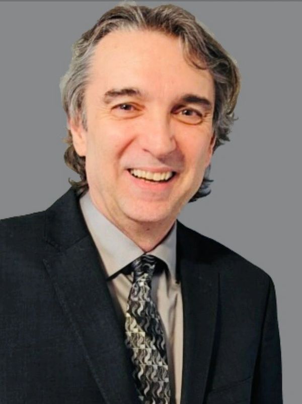 Smiling man in a suit and patterned tie.