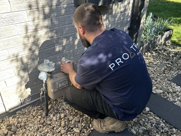 A plumber checking a gas meter outside a house.