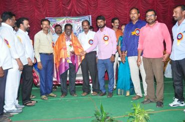 Group of people honoring a man with a shawl on a stage.