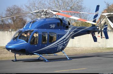 Blue Bell 429 helicopter parked on a tarmac with a pilot inside.