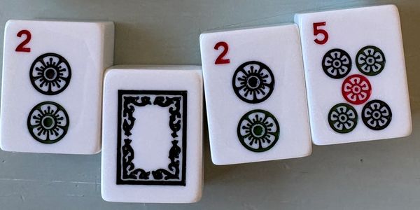 Mahjong tiles arranged in a circle on a gray surface.