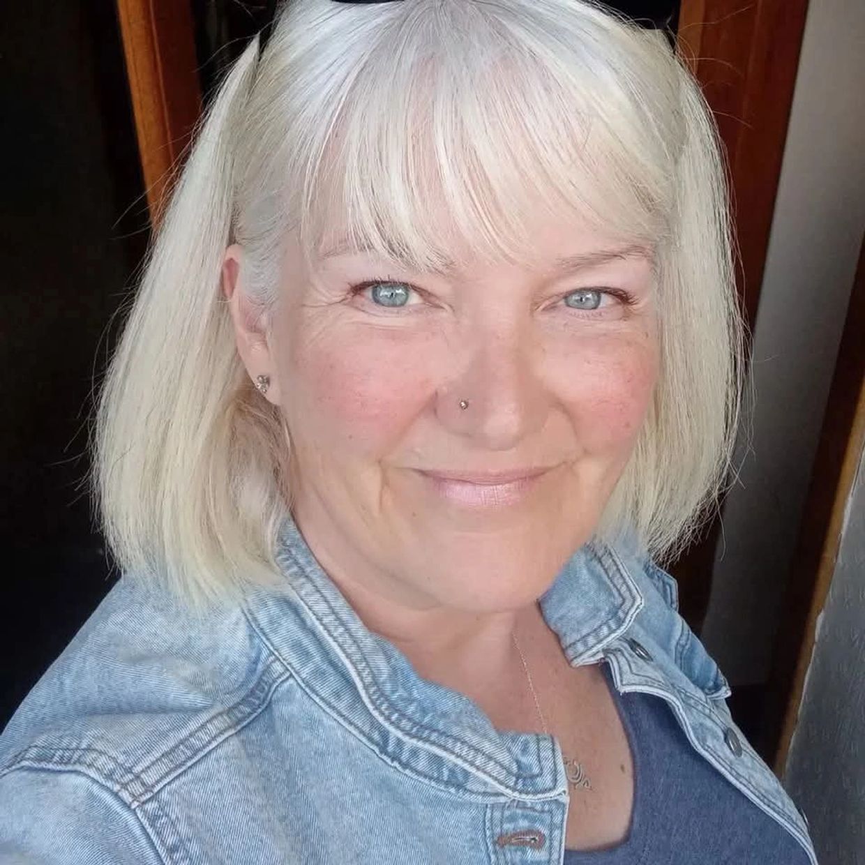 Smiling woman with blonde hair wearing a denim jacket.