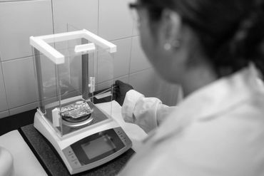 Scientist using an analytical balance to measure a sample in a lab.