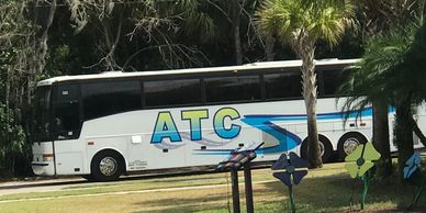 ATC Coach Charter bus parked in Daytona Beach Florida parking lot waiting surrounded by luscious veg