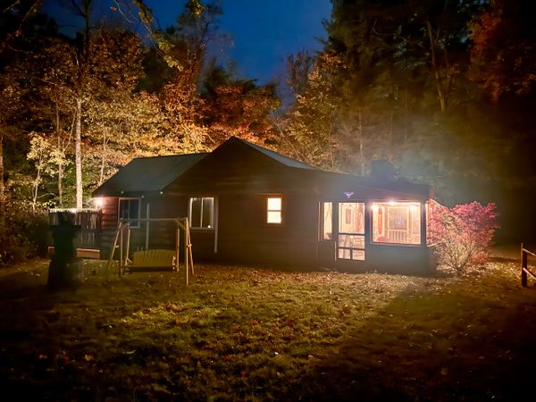 Side view of Troy's Cabin lit up from the front yard at night