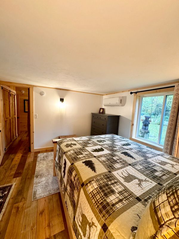 View of queen bedroom at Troy's Cabin, looking out the window where you can see the bear statue.