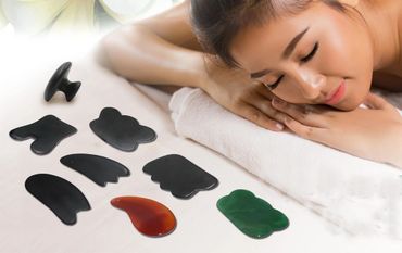Woman relaxing with gua sha massage tools laid out beside her.