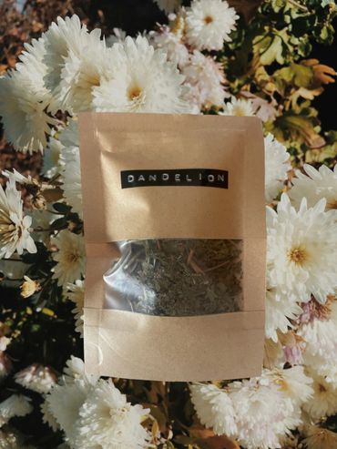 A labeled package of dried dandelion leaves against white flowers.