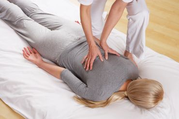 A person receiving a back massage while lying face down.
