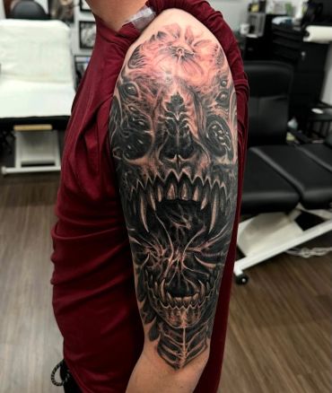 Black and gray fierce skull tattoo covering upper arm.