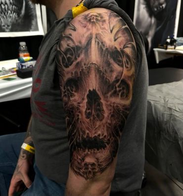 Detailed skull-themed tattoo on upper arm.
