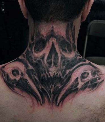 Black skull tattoo covering the neck and upper back.