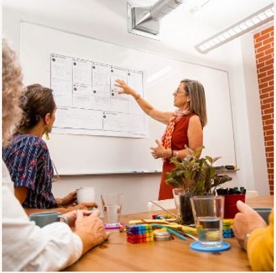 A woman presents information to a group in a meeting room.