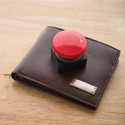 Close up red reset emergency button on leather wallet wooden background copy space
