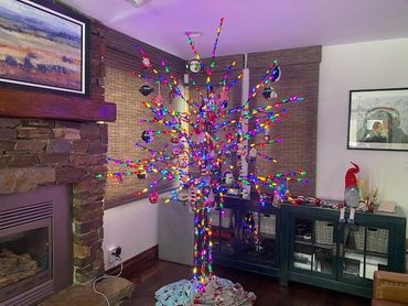 Colorful lit Christmas tree with ornaments in cozy living room corner.