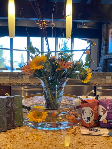 Flower arrangement with coffee and chocolate on a kitchen island.