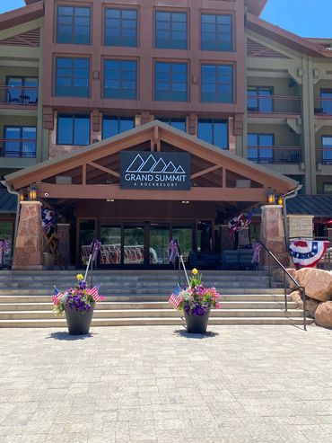 Entrance of Grand Summit RockResort with patriotic decorations and flower pots.