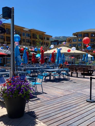 Outdoor seating area decorated with American flags and colorful lanterns under a clear blue sky.