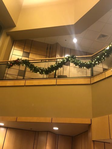 Indoor balcony decorated with illuminated Christmas garland.