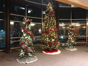 Three decorated Christmas trees with red and white ornaments inside a building.