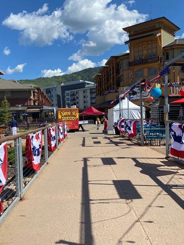 Patriotic decorations line a sunny walkway in a mountain town.