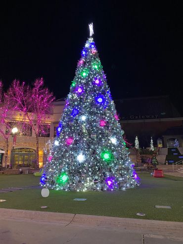 A brightly lit Christmas tree with colorful ornaments at night.