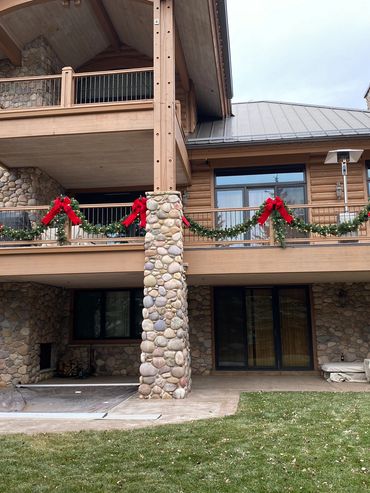 Stone cabin decorated with Christmas garlands and red bows on the balcony.