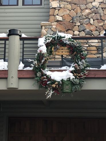 Snow-covered Christmas wreath hanging on a balcony railing.