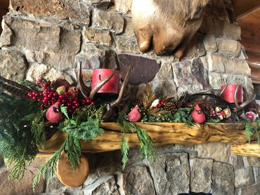 Festive holiday mantel decorated with red cardinals, greenery, pinecones, and candles.