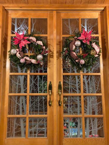 Festive Christmas wreaths with red poinsettias and ornaments on wooden doors.