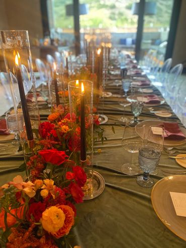 Elegant long dining table with lit candles and vibrant floral centerpiece.