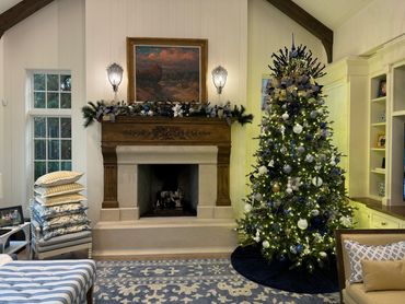 Cozy living room with a decorated Christmas tree and a wood-carved fireplace.