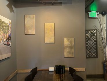 A cozy dining area with wooden table and holiday-themed wall art under warm lighting.