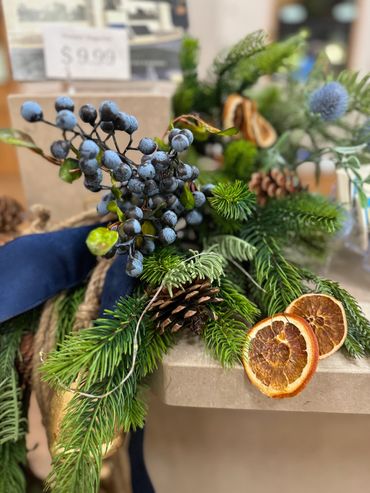 A festive greenery arrangement with pinecones, dried orange slices, and blue berries.