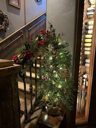 Cozy Christmas decorations with a lit mini tree and festive garland on a staircase.