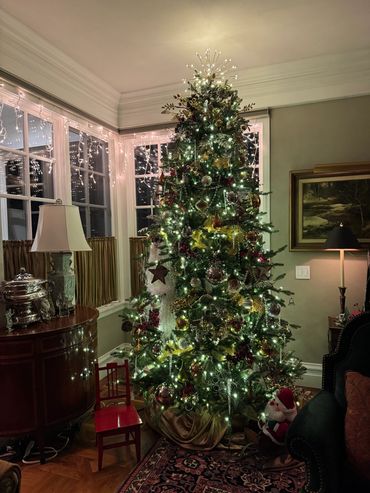 A beautifully decorated Christmas tree illuminated with white lights in a cozy living room corner.