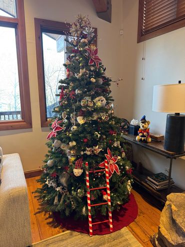 A festive Christmas tree decorated with various ornaments and a red and white candy cane ladder.