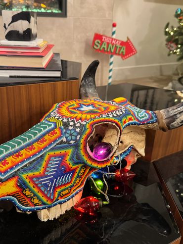 Colorful beaded bull skull with Christmas decorations on a table.