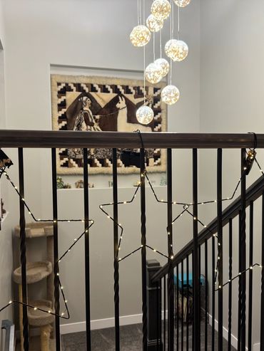 Star-shaped string lights decorate a dark staircase railing in a cozy home.