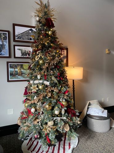 Elegantly decorated Christmas tree with gold, red, and white accents in a cozy room.
