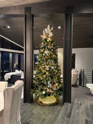 Elegant Christmas tree decorated with gold and white ornaments in a modern living room.