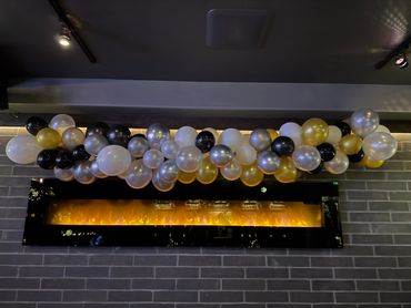 Decorative balloons above a modern fireplace on a brick wall.