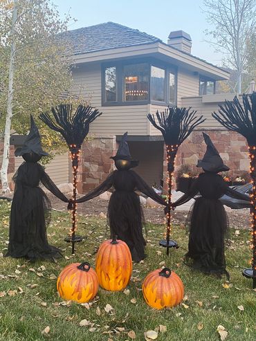 Halloween display with witches holding hands and glowing pumpkins.