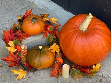 Autumn pumpkins with candle and colorful fall leaves on concrete steps.