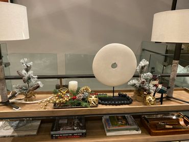 Decorative holiday centerpiece with lamps, pine cones, and a stone sculpture.