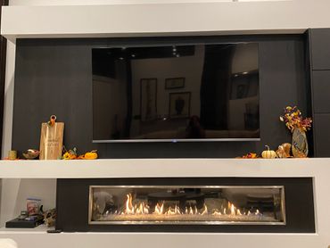 Modern fireplace with a mounted TV and autumn decorations.
